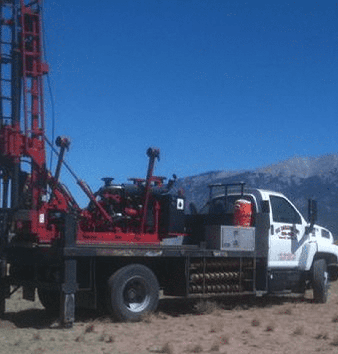 A truck with drilling equipment set against a clear blue sky.